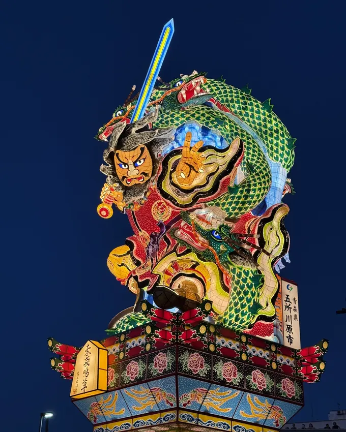 Towering Tachineputa float rising to its full height against the deep-blue evening sky, Goshogawara